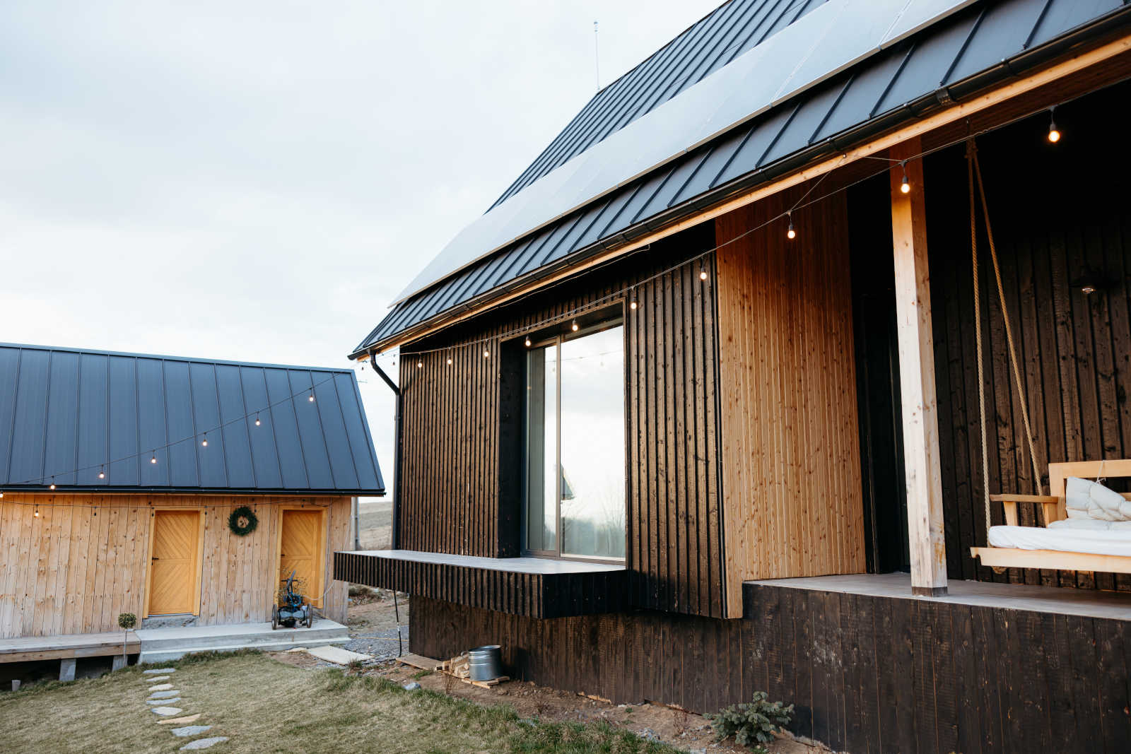 Ansicht eines Holzhauses mit Nebengebäude und Solaranlage auf dem Dach